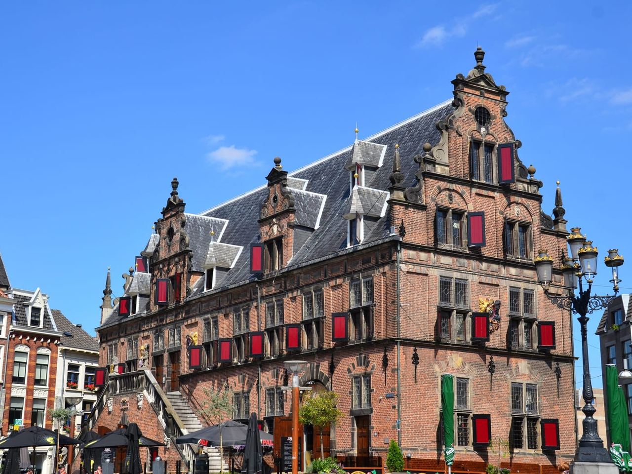 Plein met bakstenen verharding, straatlantaarns, straatmeubilair en historische bebouwing